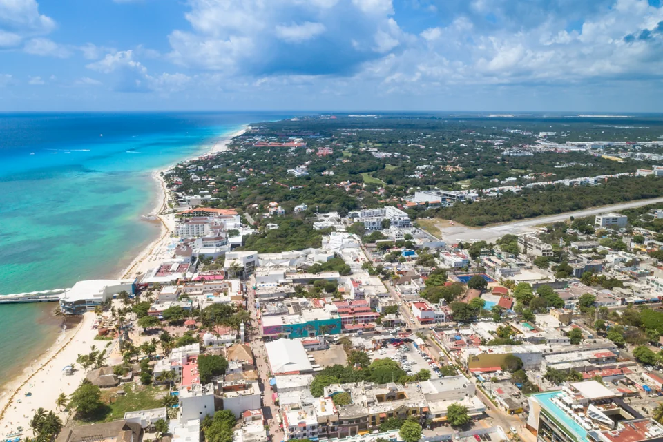 An aerial view of the turquoise Caribbean shore, the pier and the town of Playa del Carmen