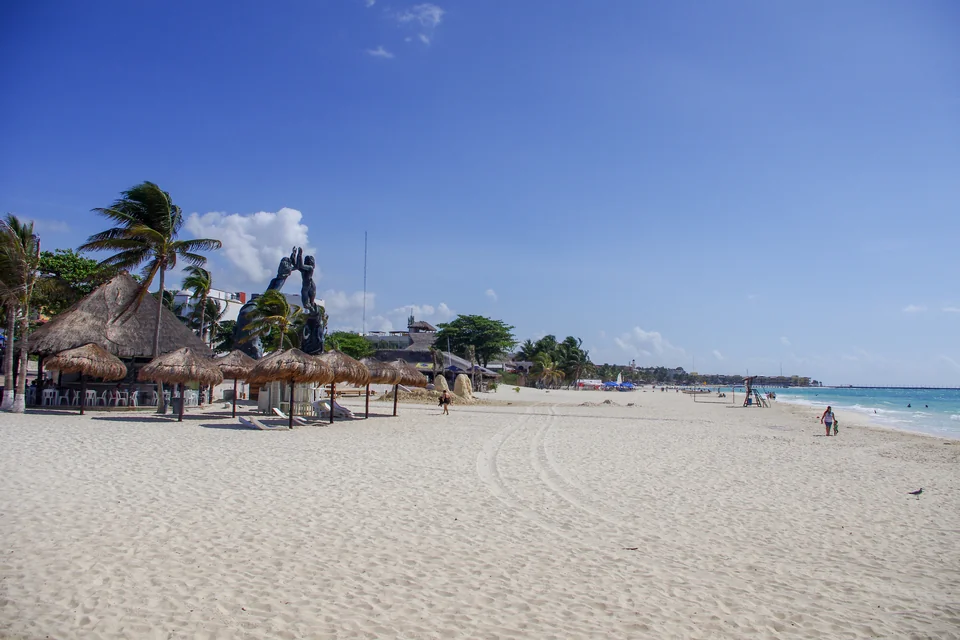 A wide white sand beach with straw umbrellas in Playa del Carmen