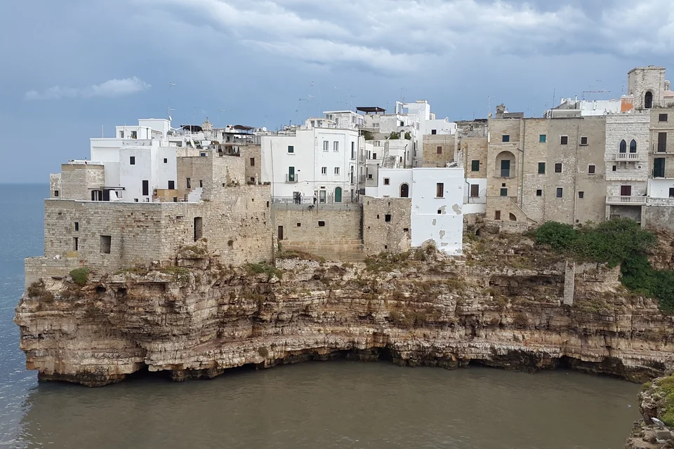 White and stone houses on the cliff jutting into the sea at Polignano a Mare