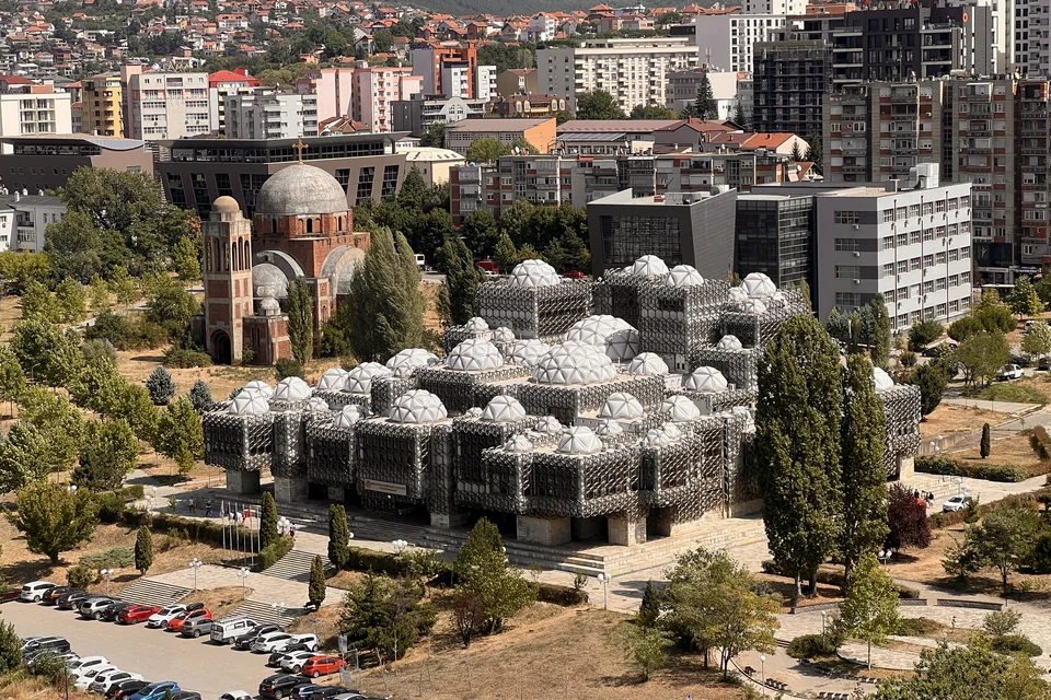 The domed lattice-clad National Library, a church and city buildings in Pristina, seen from above