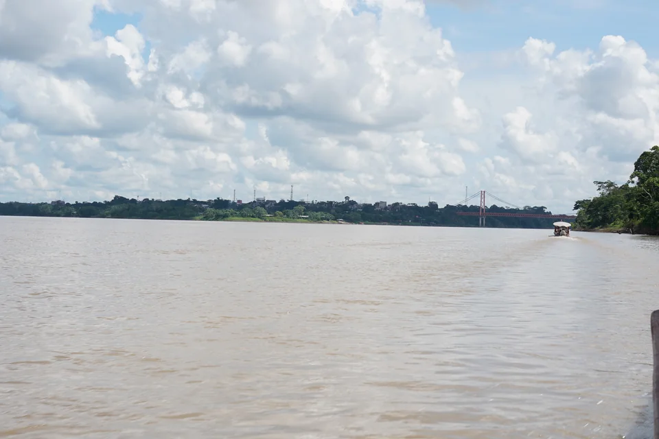 The wide Madre de Dios River with a suspension bridge in the distance, Puerto Maldonado