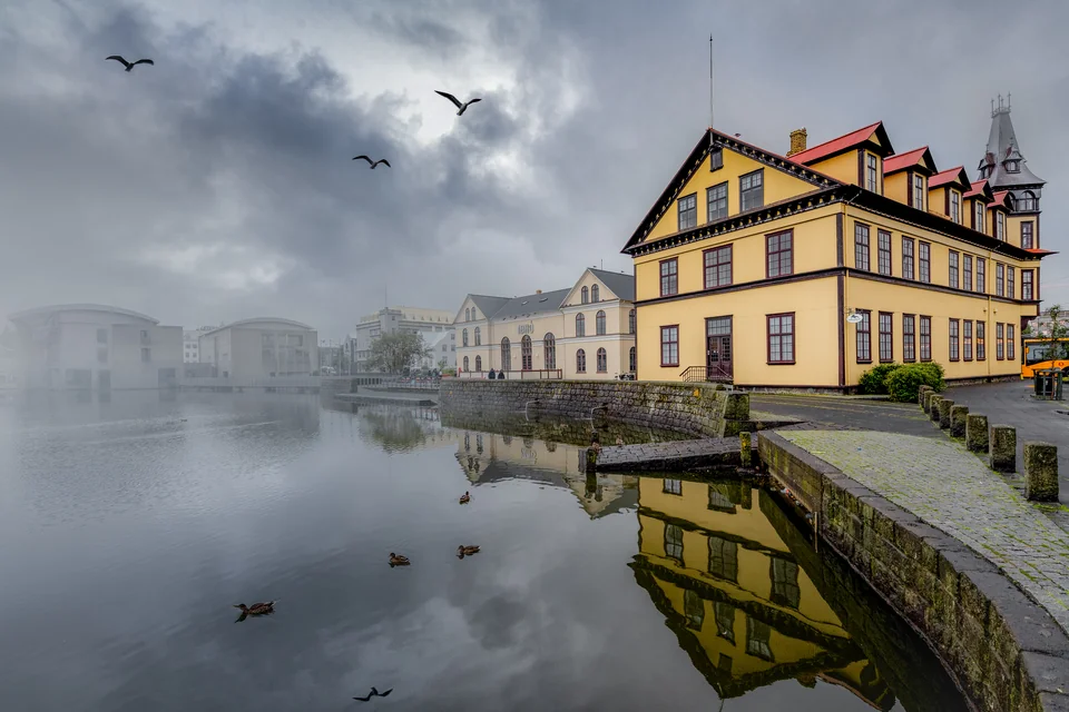 Historic yellow-fronted buildings reflected in Lake Tjörnin, Reykjavik