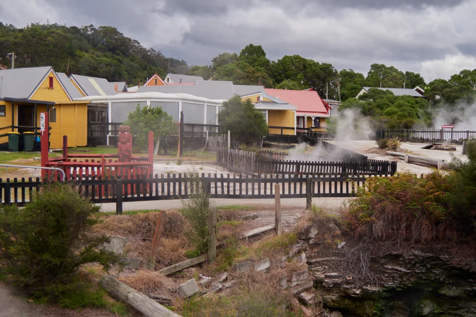 Steaming hot springs and colourful timber houses in Whakarewarewa thermal village, Rotorua