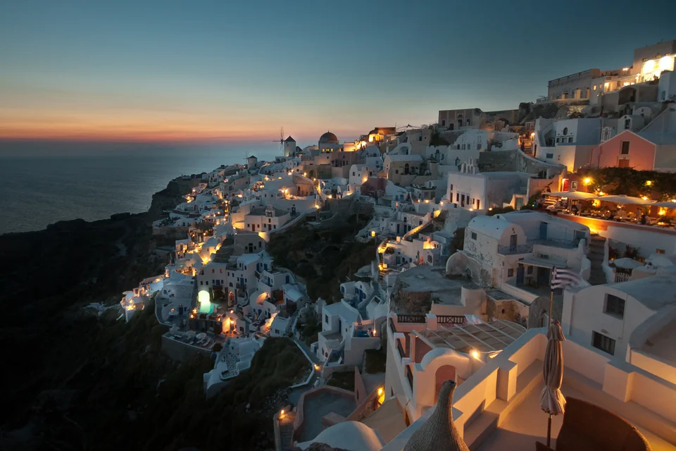 The white houses of Oia on the hillside and a windmill at dusk, Santorini