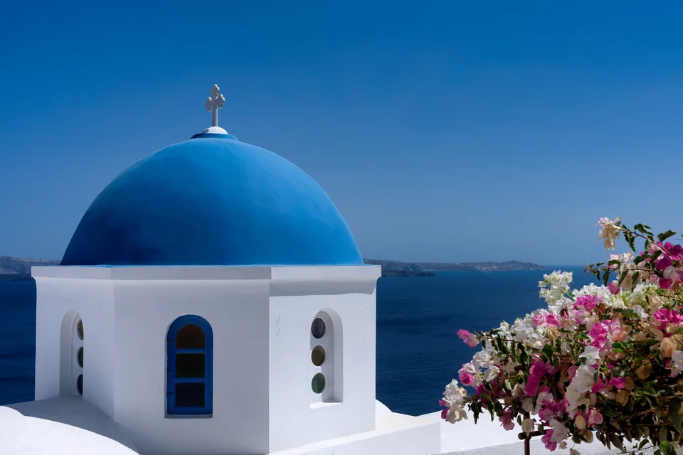 A blue-domed church, bougainvillea and the sea on Santorini