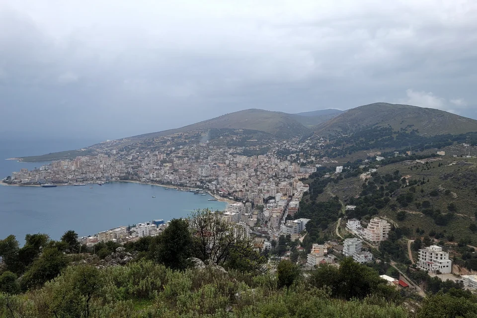 Saranda spreading along its bay seen from the hills with green slopes