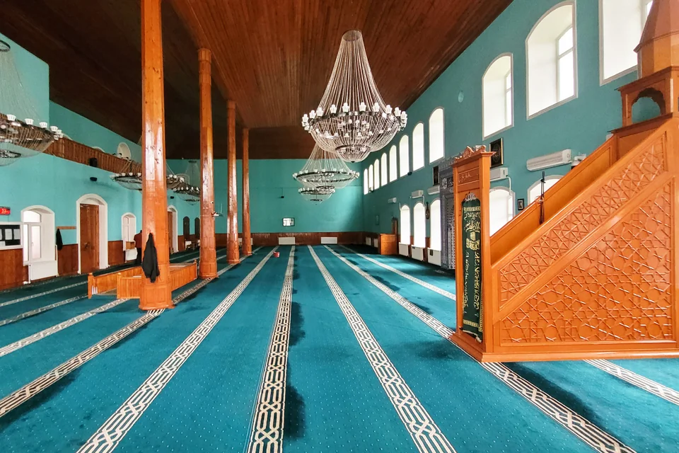 Turquoise walls, a carved wooden minbar and chandeliers in the Juma Mosque of Shaki