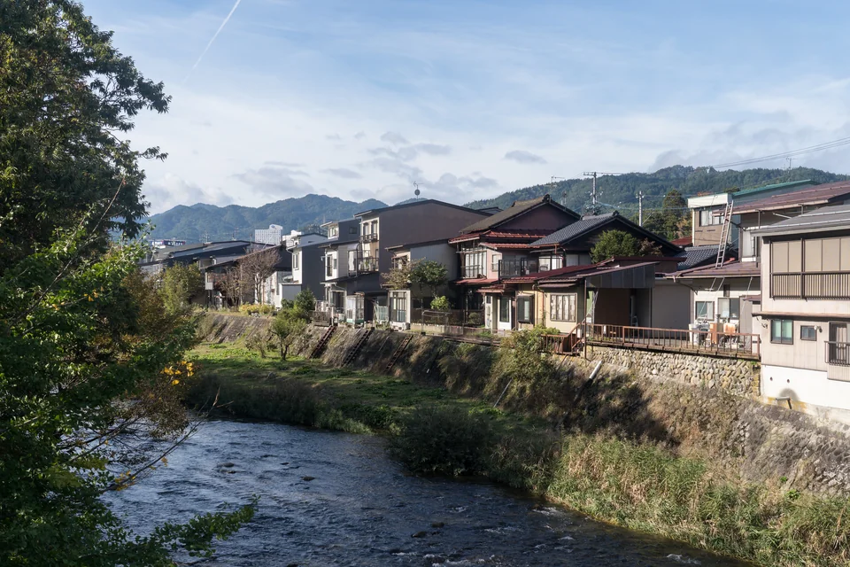 The Miya River, green banks and forested mountains behind in Takayama