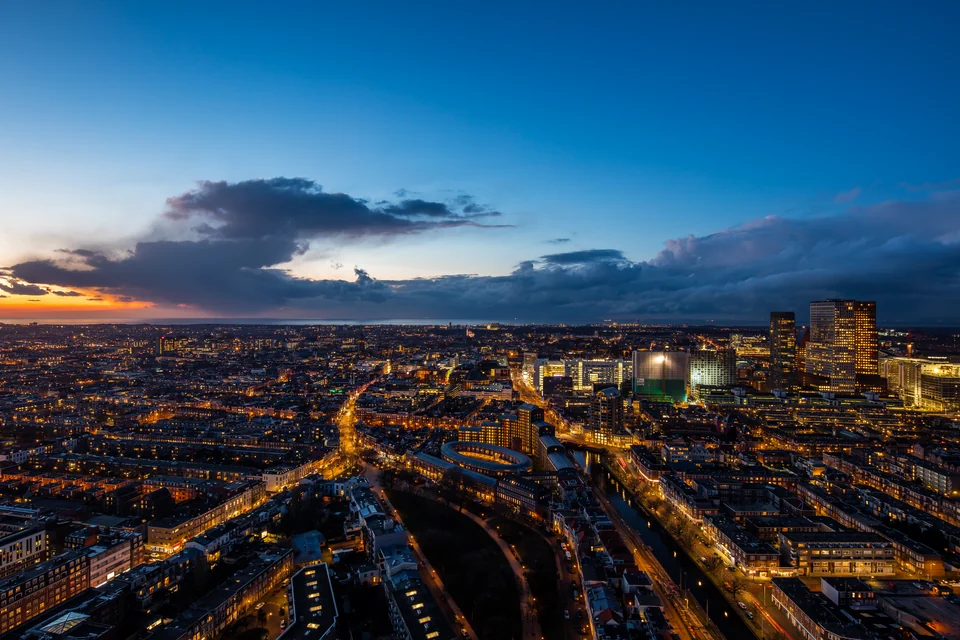 The Hague lighting up at dusk with its towers and the North Sea on the horizon