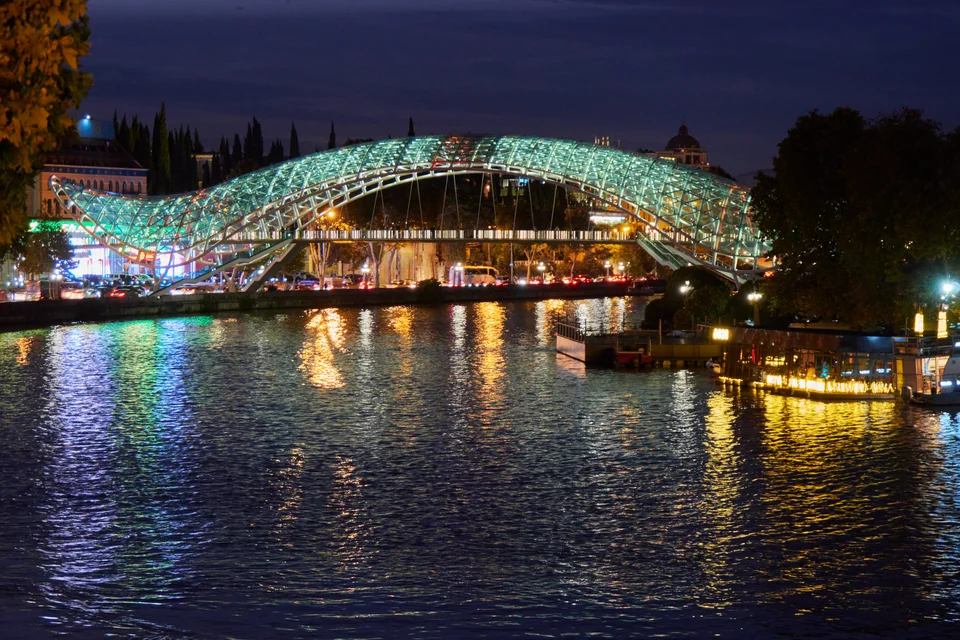 The illuminated Bridge of Peace and the Kura River at night in Tbilisi