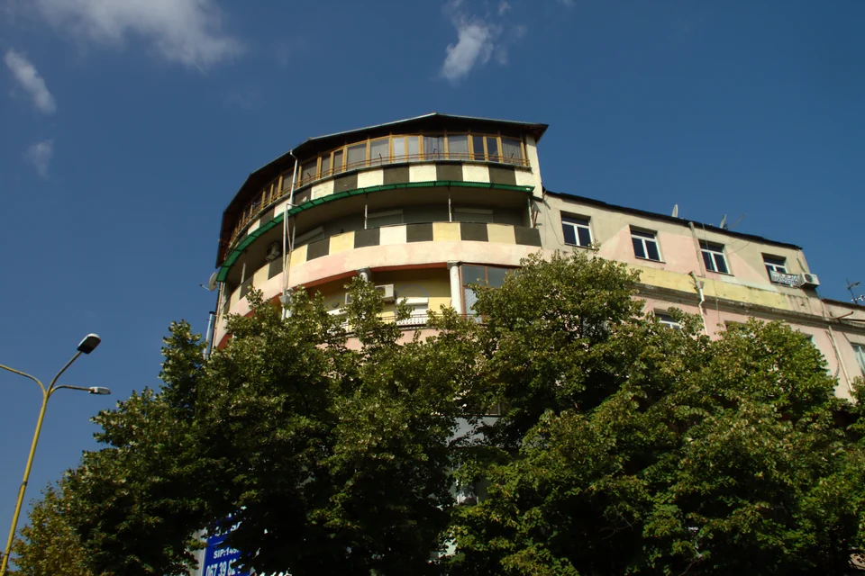 A colourful historic corner building and pines in Tirana