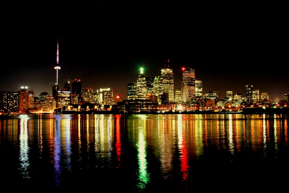 The Toronto skyline and CN Tower with night lights reflected in the lake