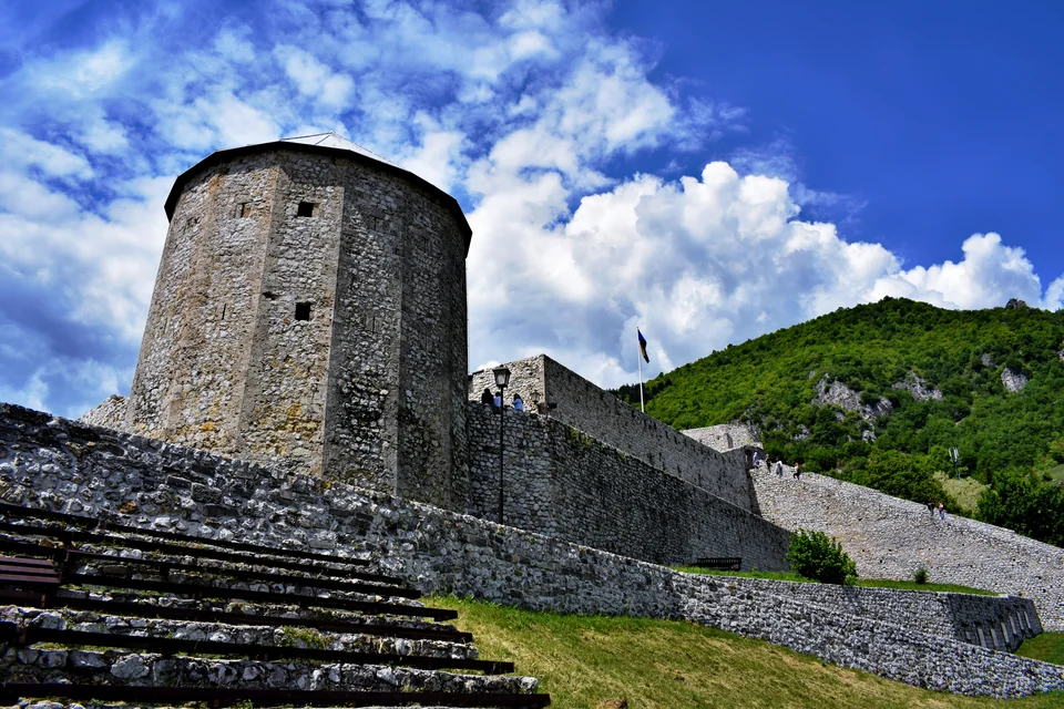 The stone tower and walls of the medieval fortress on a green hill in Travnik