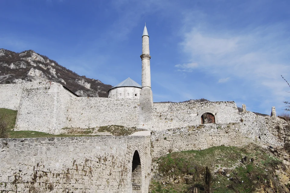 The stone walls of Travnik fortress, a minaret and the rocky mountain behind