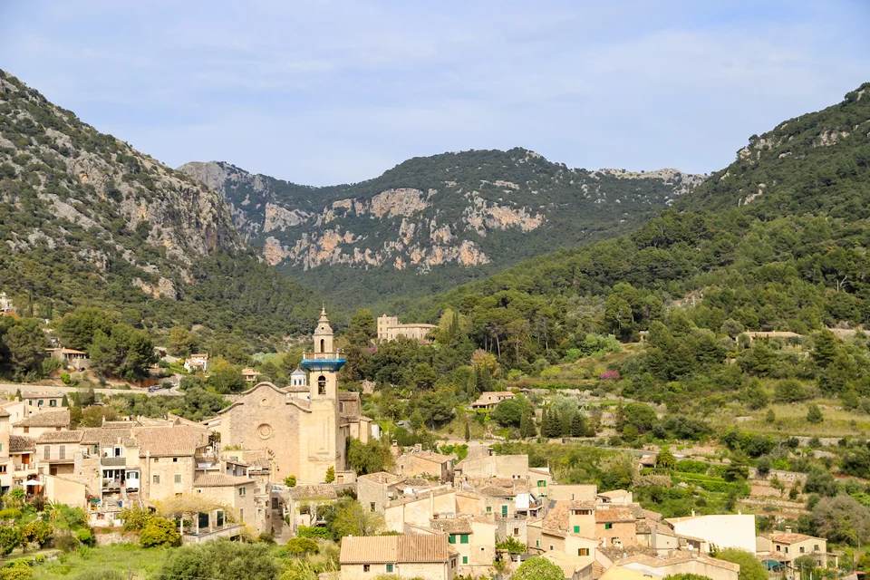 A bell-towered church, stone houses and the wooded valley at Valldemossa