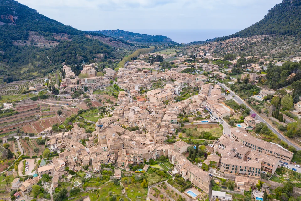 Terraced slopes and the stone village in a valley opening to the sea, Valldemossa
