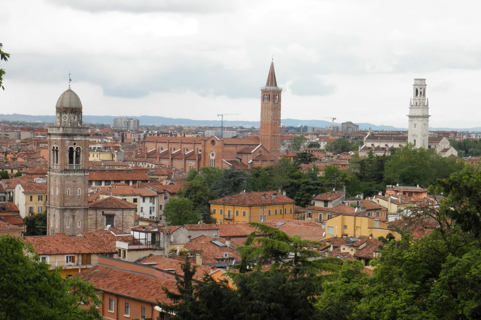 Bell towers and a dome rising above the red rooftops of Verona