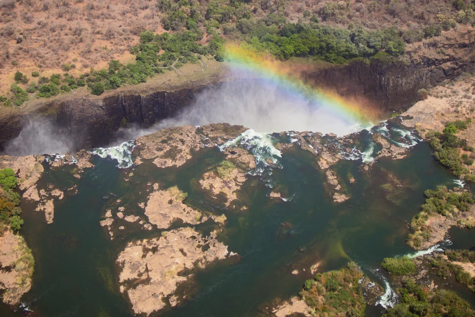 An aerial view of Victoria Falls, the Zambezi River and a rainbow
