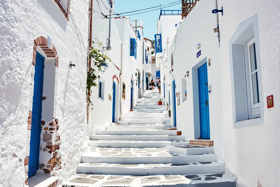 A stepped stone street with blue doors between whitewashed houses in Greece