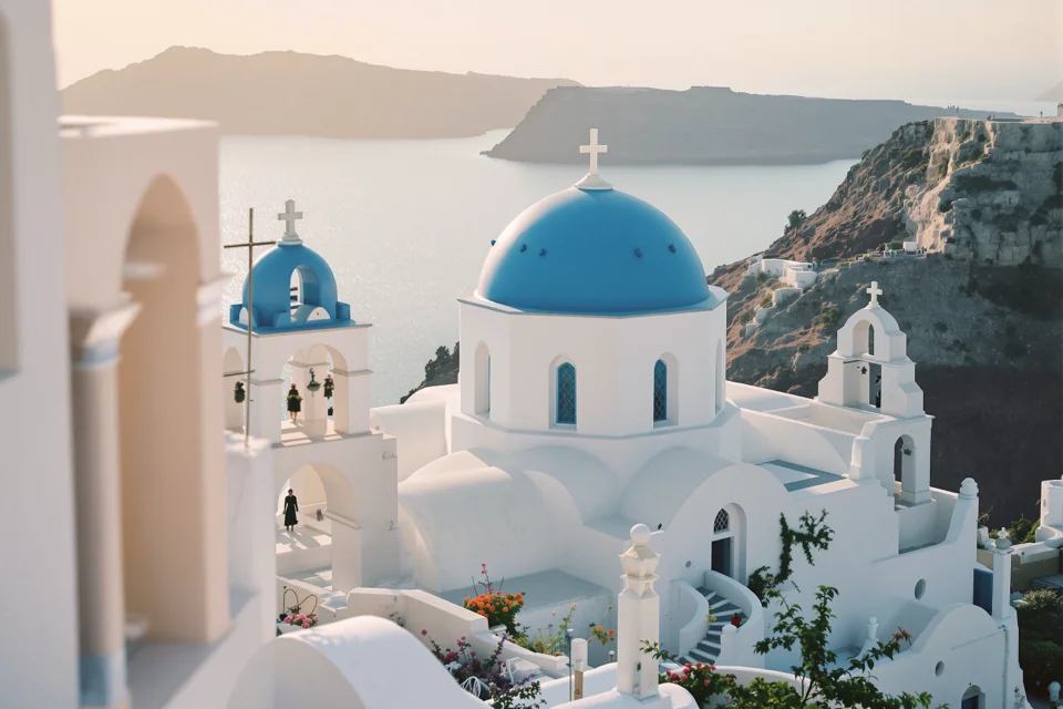 A small whitewashed chapel with a blue dome on a clifftop in Greece