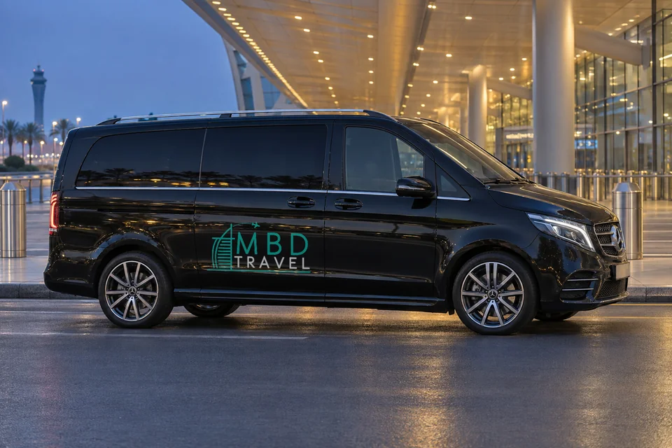 Black Mercedes-Benz Vito private transfer vehicle with MBD Travel livery outside an airport terminal at dusk, visualization