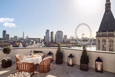 Londra çatısında iki kişilik kurulu masa; arkada Thames, London Eye ve şehir silueti